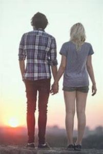 Couple, de dos, main dans la main, devant un lever de soleil
